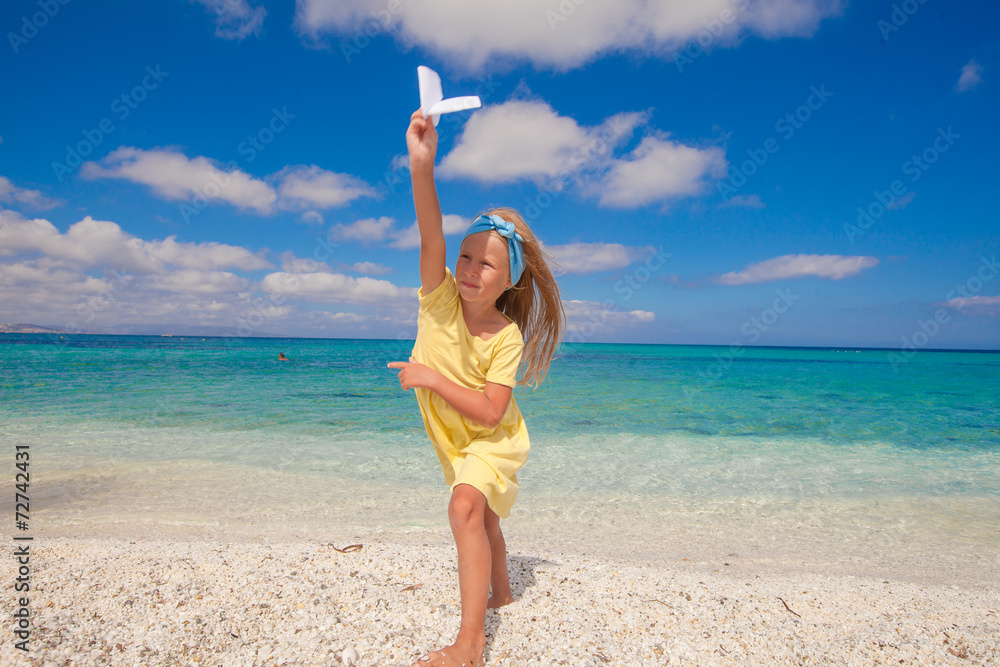 Happy little girl with paper airplane during beach vacation Happy little girl with paper airplane during beach vacation
