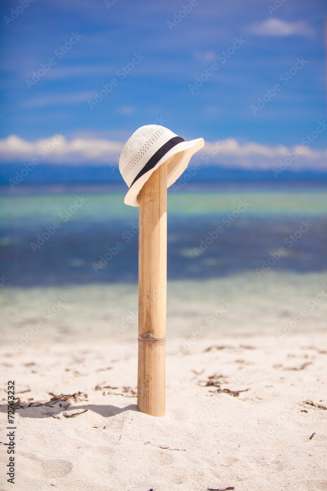 Straw hat at wooden fence on white sandy beach
