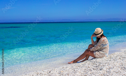 Young beautiful girl during summer vacation on white beach