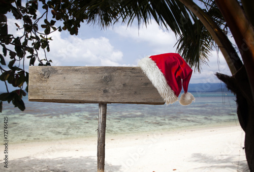 Wooden signboard with Christmas hat on tropical beach