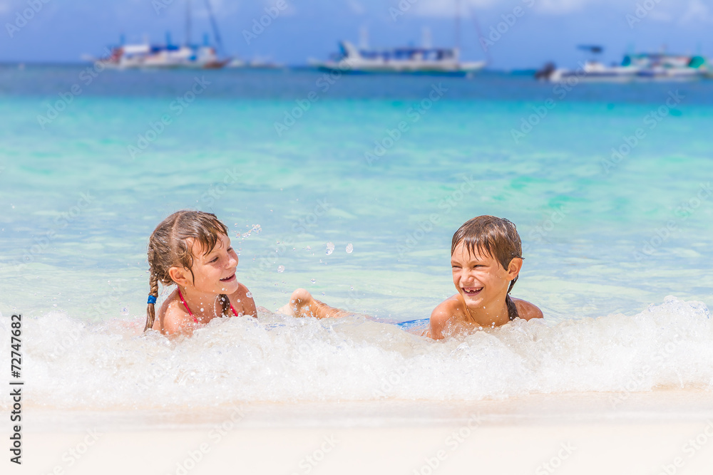 two young happy children - girl and boy - having fun in water, t two young happy children - girl and boy - having fun in water, t