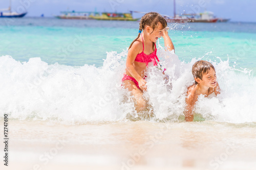 two young happy children - girl and boy - having fun in water, t