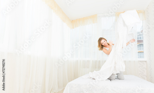 Pretty young woman enjoying morning time at her house lying in b