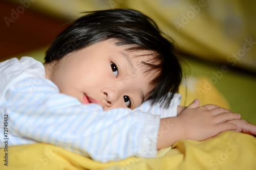 Cute Asian child lying on bed.