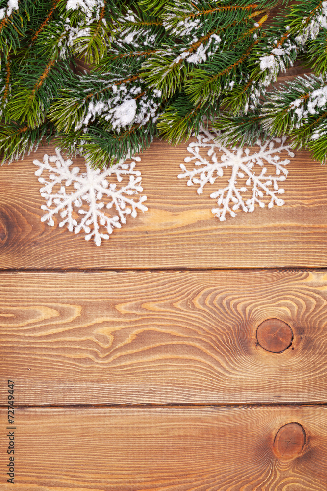 Christmas fir tree with snow and snowflake decor on rustic woode Christmas fir tree with snow and snowflake decor on rustic woode