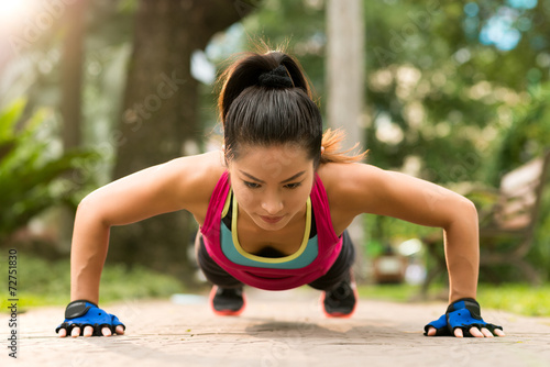 Sporty Asian woman doing push-ups outdoors