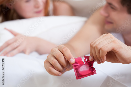 Male hands opening condom