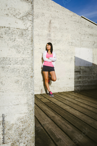 Female athlete leaning against wall with arms crossed