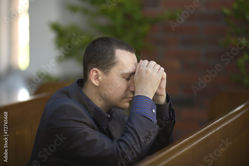 Handsome young man praying in a church
