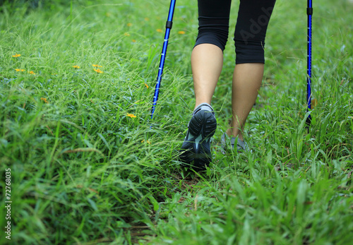 young fitness woman hiker legs walking on green grass trail 