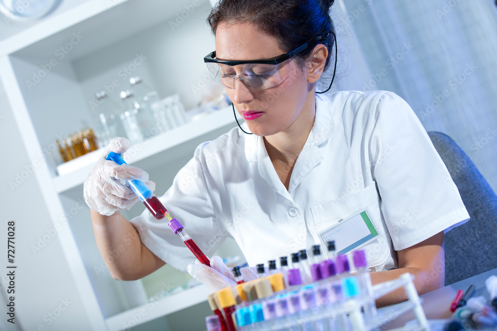 Close up of a protected scientist dropping liquid in a test tube