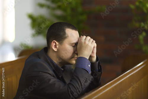Handsome young man praying in a church