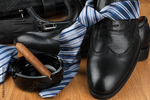 Classic men's shoes, tie, umbrella, cigar, ashtray and bag on t
