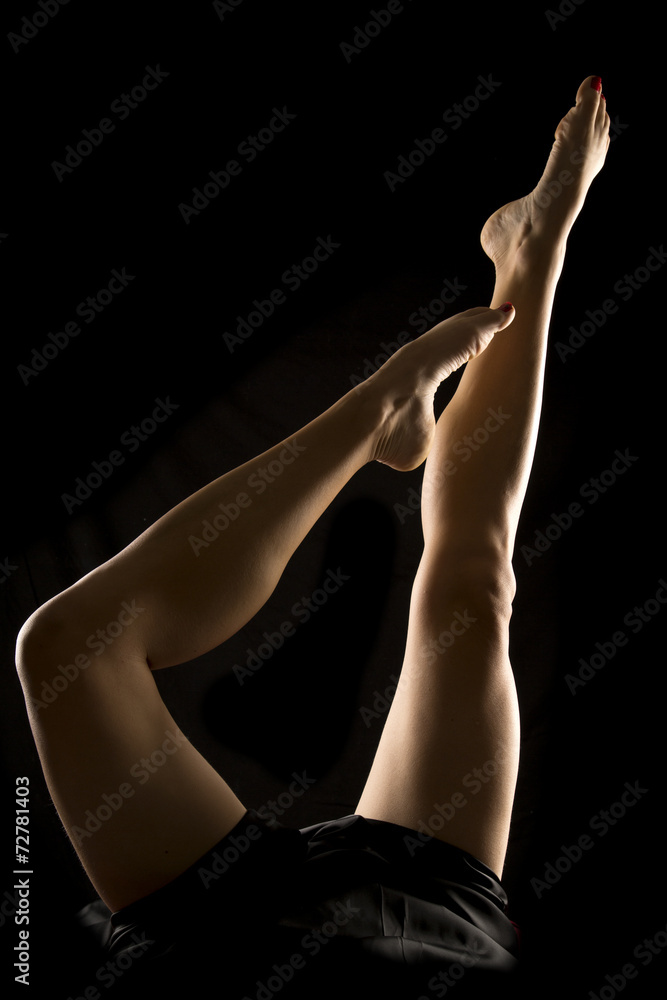 Naklejka premium woman legs up on black back lit one up one pointed