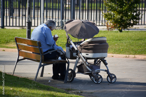 abuelo dando de comer a su nieto en un parque photo