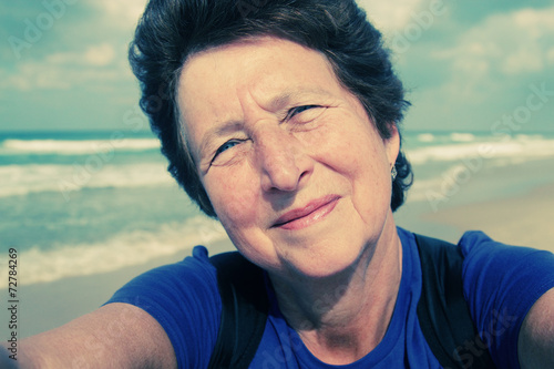 Selfie portait of happy senior woman on the beach