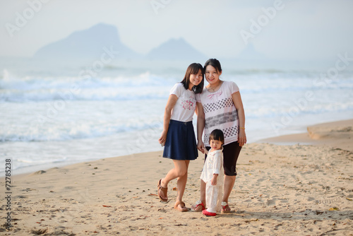 Happy Asian family, mother, sister and child on the beach.