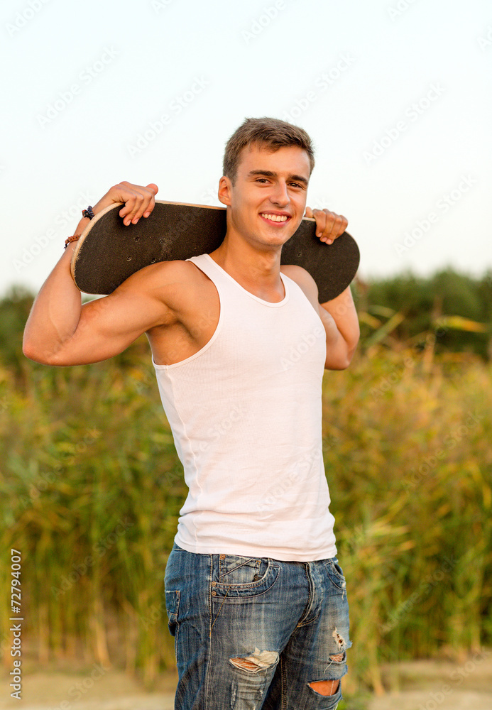 Fototapeta premium smiling teenage boy with skateboard outdoors