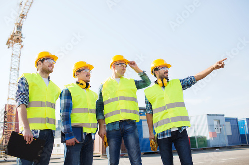 group of smiling builders with tablet pc outdoors