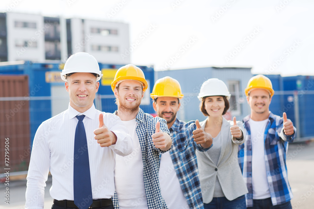 group of smiling builders in hardhats outdoors group of smiling builders in hardhats outdoors
