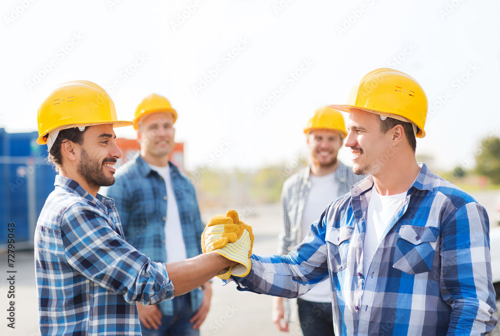 group of smiling builders shaking hands outdoors group of smiling builders shaking hands outdoors