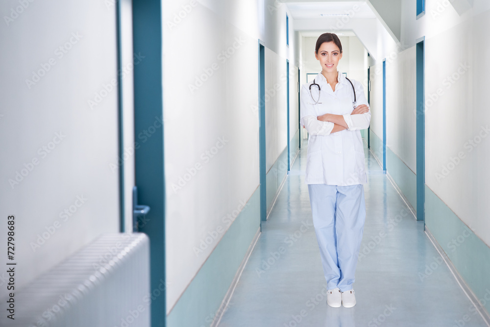 Female Doctor Standing Arms Crossed In Hospital Corridor Female Doctor Standing Arms Crossed In Hospital Corridor