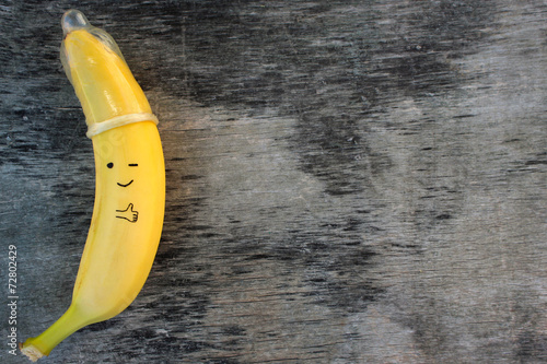 Banana with condom  on the old wooden background.
