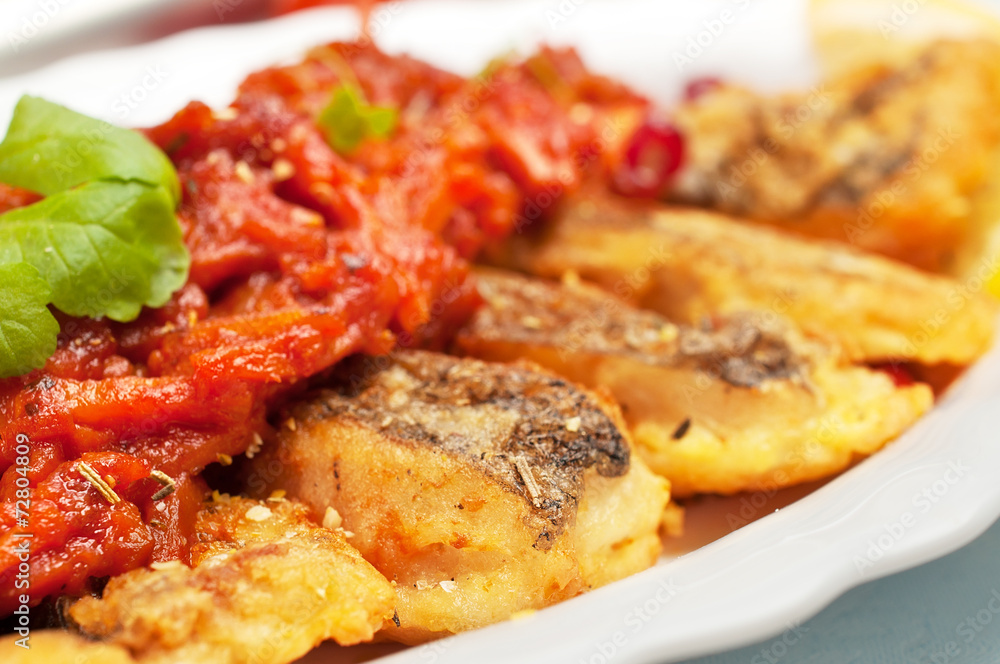 Pieces of fried fish under the carrot sauce