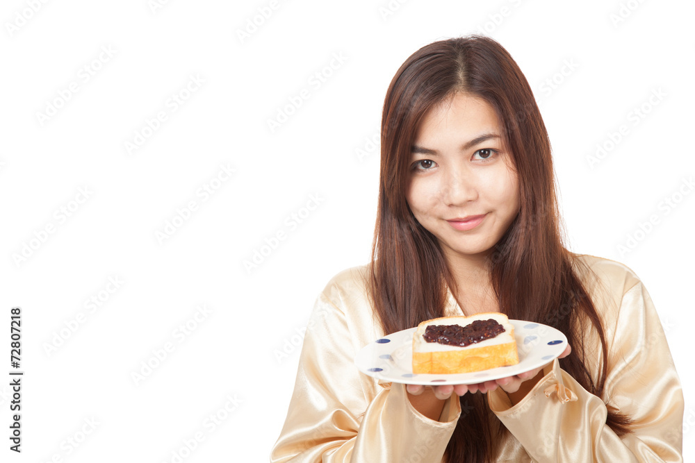 Asian woman in pajamas with bread and heart shape berry jam