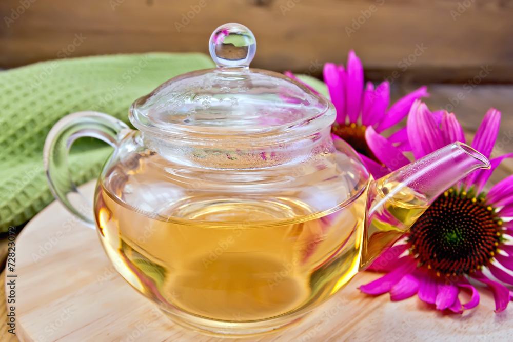 Tea from Echinacea in glass teapot on board with cloth Tea from Echinacea in glass teapot on board with cloth