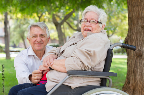 Man and senior woman in wheel chair talking at the park