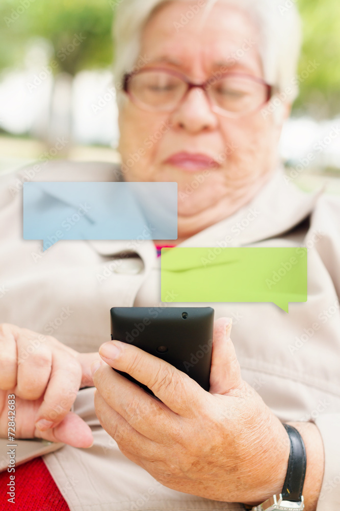 Senior woman typing a message with smartphone with limited dof Senior woman typing a message with smartphone with limited dof