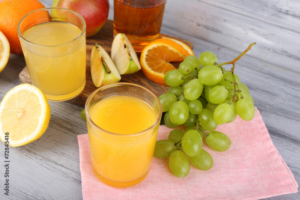 Fototapeta premium glasses of juice with fresh fruits on grey wooden table
