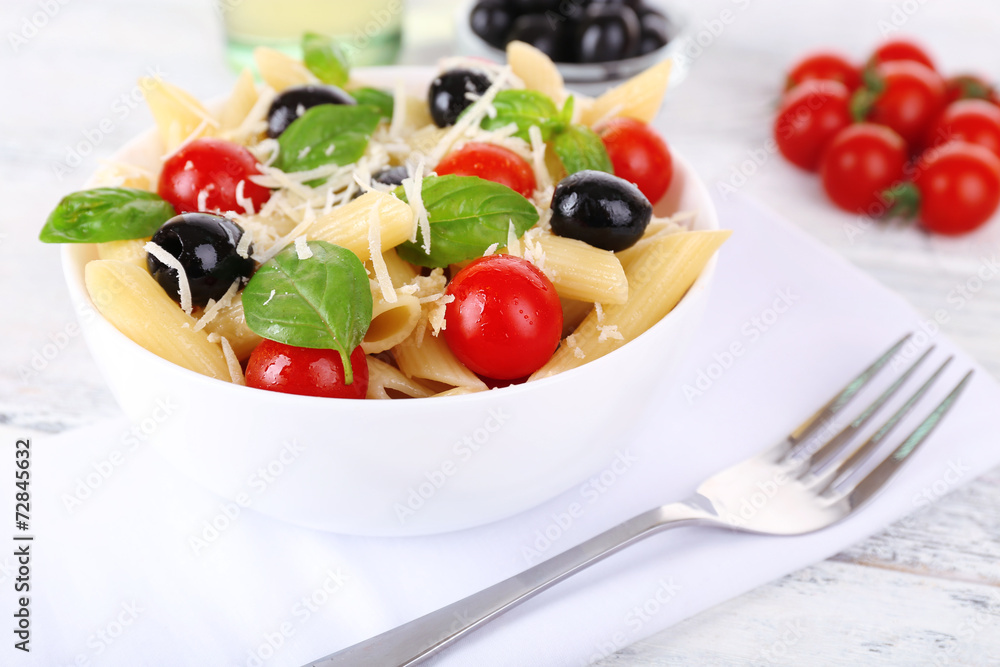 Pasta with tomatoes, olives and basil leaves in bowl