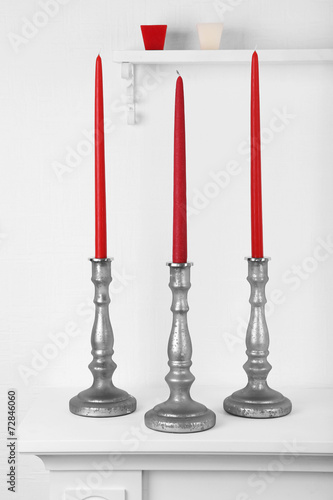 Red candles in candle holders on table on white background photo