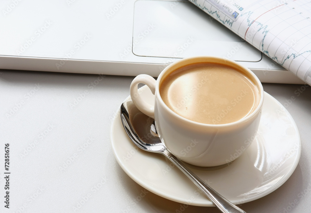 A cup of coffee, paper on a laptop. A cup of coffee, paper on a laptop.