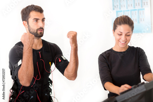 Fotografie Female coach giving man ems electro muscular stimulation exercis
