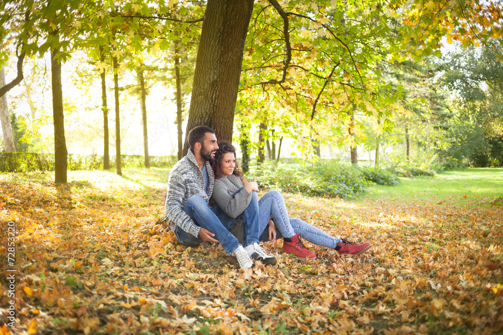 happy young couple leaning against a tree enjoying the autumn in