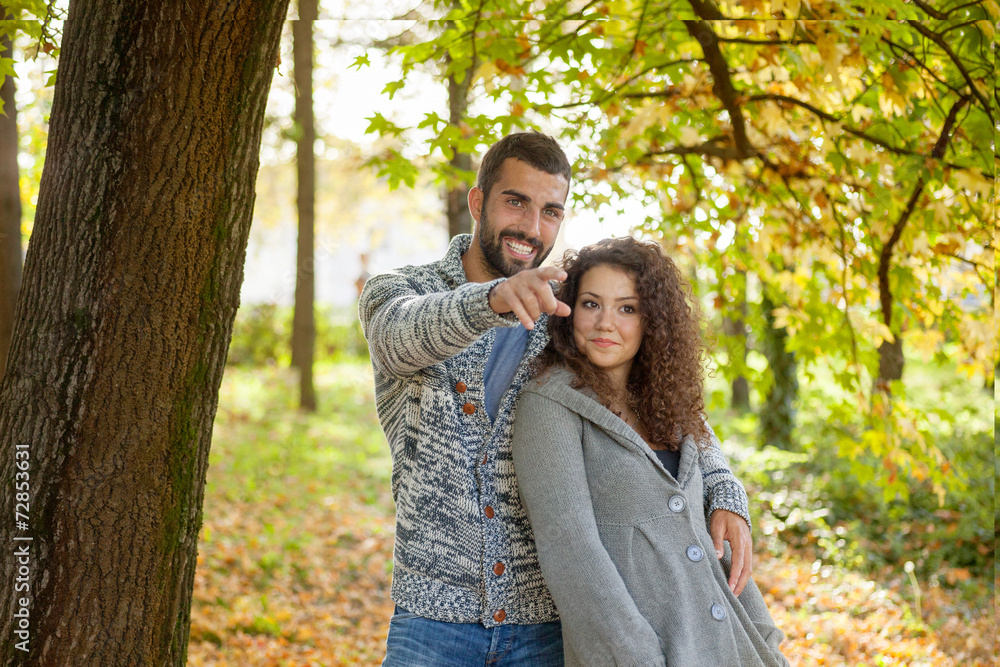 happy young couple leaning against a tree enjoying the autumn in
