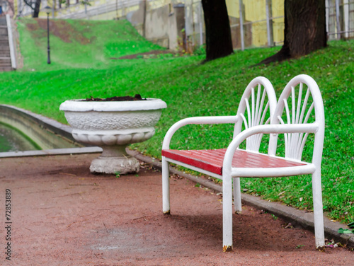 red-white wooden bench in the park on the green grass background © OlegKovalevich