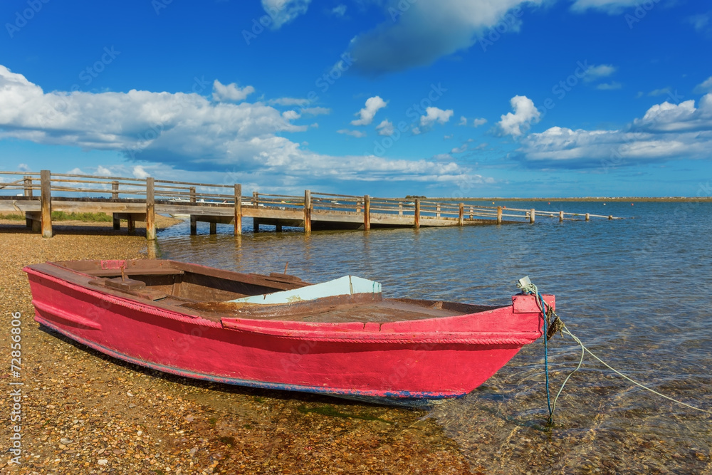 Red fishing boat on the shore. Near the bridge.