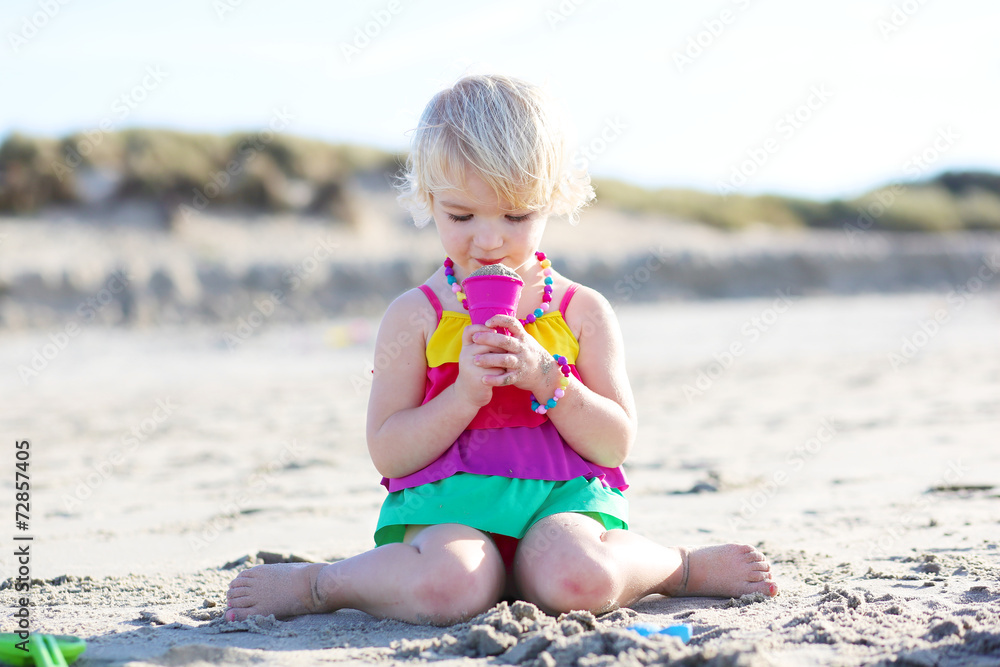 Little happy girl having fun playing on the beach
