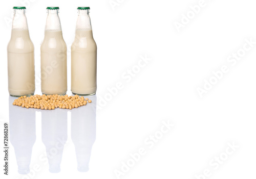 Soybean and bottles of soybean milk over white background photo