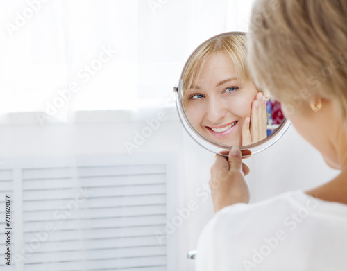 beautiful young woman in the morning, looks in the mirror