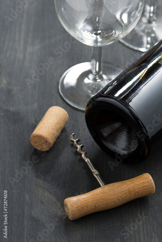 bottle of red wine, glasses and  corkscrew on wood