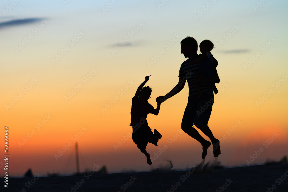 Father and kids jumping at sunset