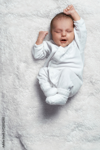 Φωτογραφία infant yawning stretches on  white fur
