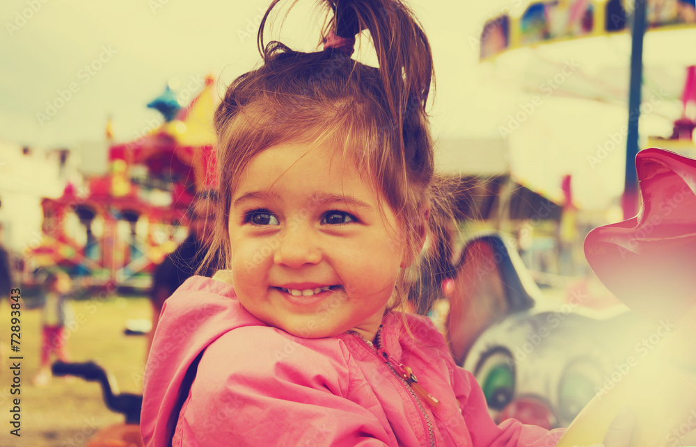 Toned portrait of happy cute smiling girl riding on carousel Toned portrait of happy cute smiling girl riding on carousel
