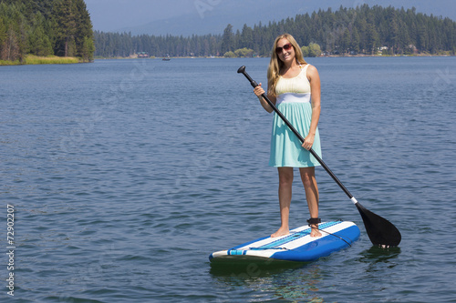 Beautiful woman paddleboarding on scenic lake