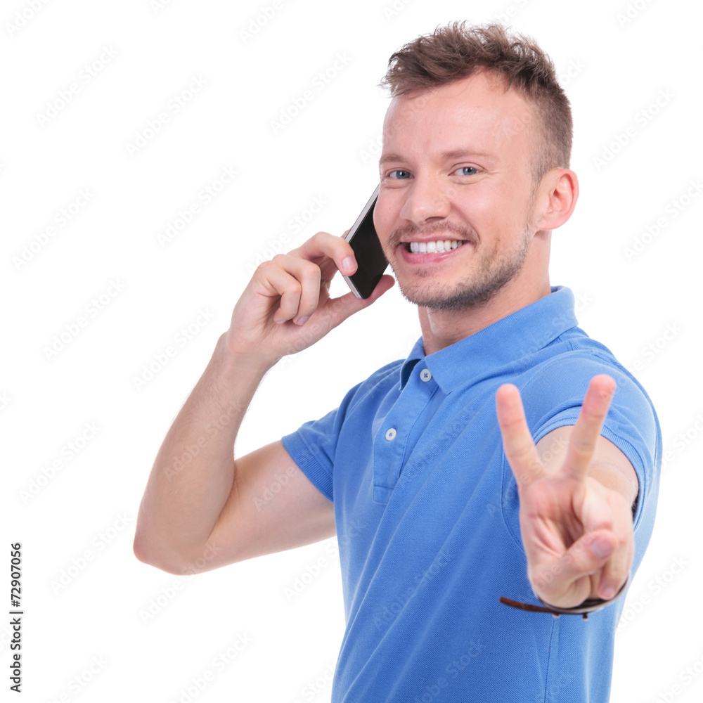 casual young man shows victory over the phone casual young man shows victory over the phone